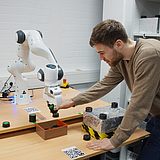 Person arbeitet mit einem Roboterarm 
