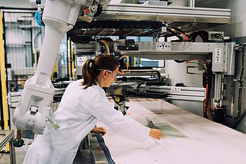 Person in Schutzkleidung bei der Arbeit an einer Maschine