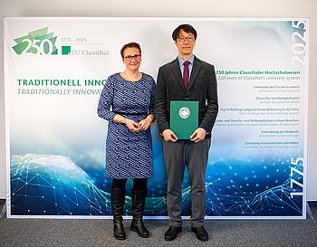 Die Tu-Präsidentin und Prof. Paek stehen vor der TU-Fotowand mit der Urkunde.