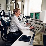 Eine Person sitzt in einem Kontrollraum und schaut auf einen Bildschirm